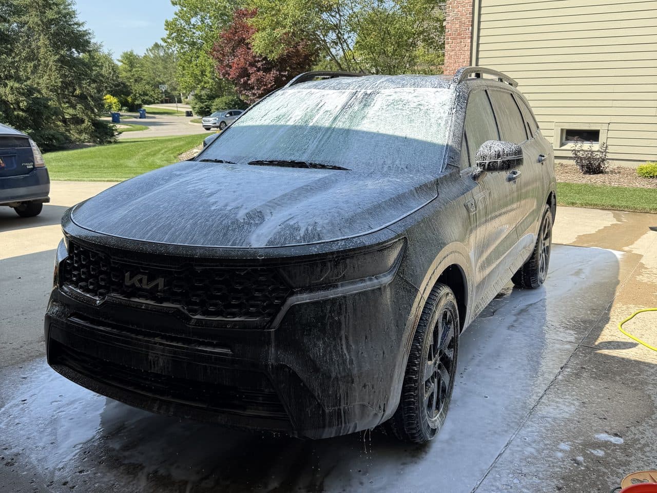An SUV covered in wash foam during an on-site exterior detail