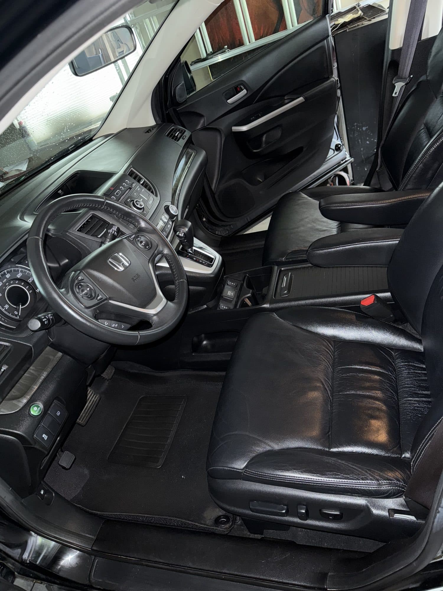 A detailed car interior with clean black leather seats, a spotless steering wheel and dashboard
